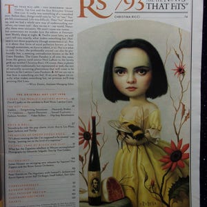 May include: A magazine cover featuring a painting of a young girl with dark hair holding a bee. The magazine is titled "Rolling Stone" and the issue number is 793. The cover also features the text "All the News That Fits" and the name "Christina Ricci".