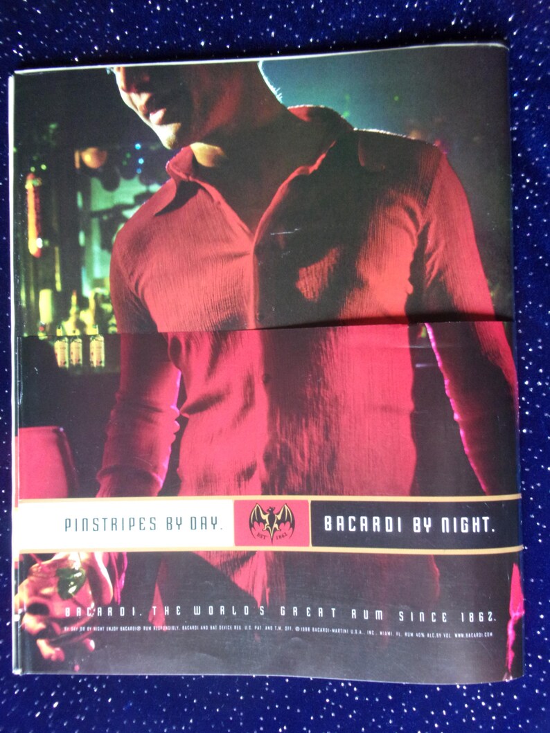 May include: A man wearing a red shirt with the text "Pinstripes by Day. Bacardi by Night. Bacardi. The World's Great Rum Since 1862." printed on the bottom.