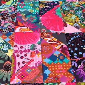 Könnte beinhalten: Eine bunte Patchwork-Decke mit verschiedenen floralen und geometrischen Mustern in den Farben Rosa, Grün, Blau und Braun.
