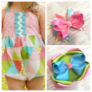 May include: Two large hair bows, one pink and one blue with green and pink accents. The bows are made of satin ribbon and are tied together in the center.