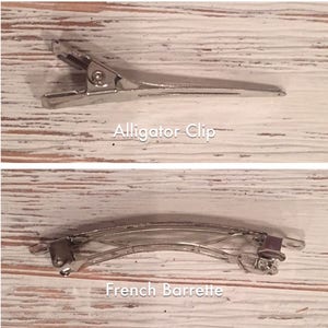 May include: Two types of hair clips: a silver alligator clip and a silver French barrette. The alligator clip is a simple, straight clip, while the French barrette is curved and has a more intricate design.