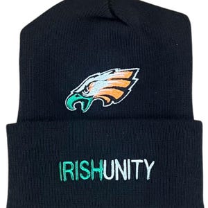 May include: Black knit beanie featuring an embroidered eagle head logo in green, orange, and white. The word "IRISHUNITY" is embroidered in green and white on the folded brim. A winter hat for fans.