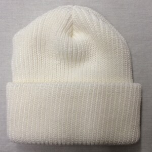 May include: A white knitted beanie hat with a ribbed texture.