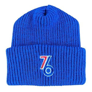 May include: A blue knitted beanie with a white and red embroidered "76" logo.