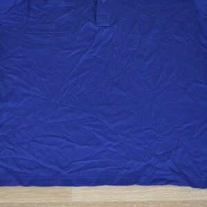 May include: A blue long-sleeved shirt with a button-up collar and a pocket on the left chest.