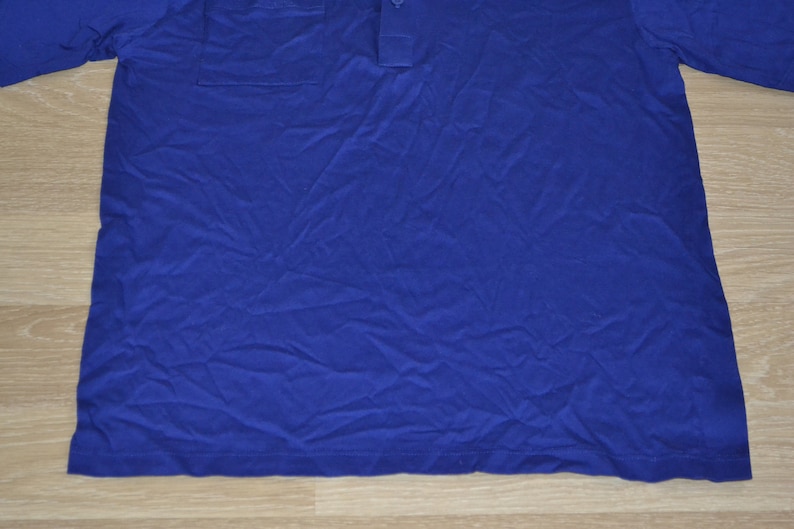 May include: A blue long-sleeved shirt with a button-up collar and a pocket on the left chest.