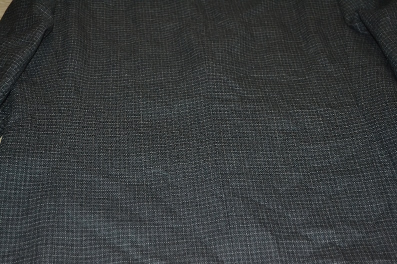 May include: A dark gray blazer with a subtle, fine white pinstripe pattern. The fabric has a textured, woven appearance.