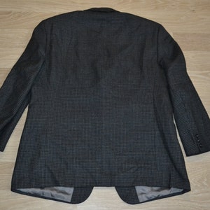 May include: A dark gray blazer with a subtle checkered pattern. The blazer has a single button closure and long sleeves.