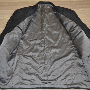 May include: A black and gray checkered blazer with a gray satin lining. The blazer has a pocket on the inside with a "Bugatchi" label.