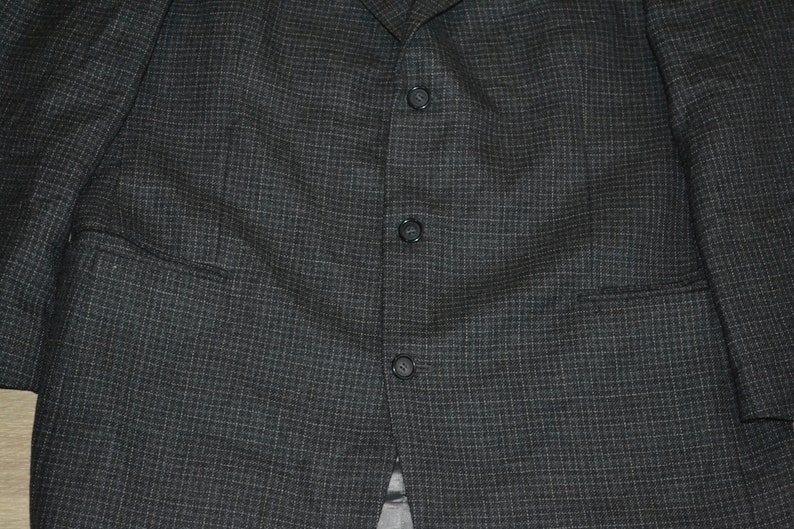 May include: A dark gray blazer with a subtle checkered pattern and a single button closure.