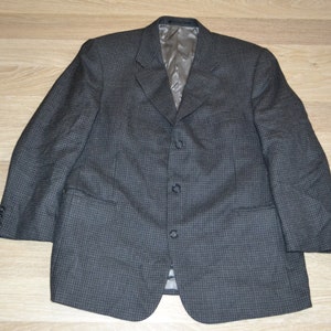 May include: A gray checkered blazer with three buttons. The blazer has a notch lapel and flap pockets.
