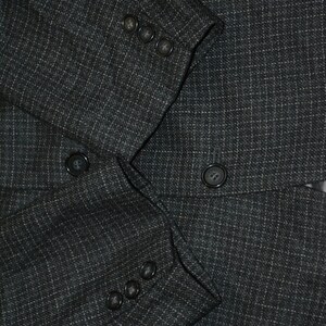 May include: A dark gray blazer with a subtle pinstripe pattern. The blazer has a double-breasted closure with four buttons on each side.