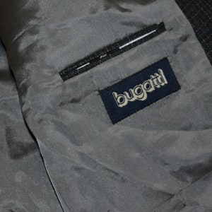 May include: A close-up of the inside of a gray jacket with a navy blue label that says "bugatti" in white lettering.