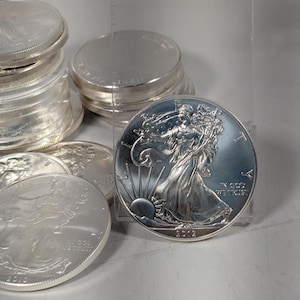 May include: A collection of silver American Eagle coins featuring the walking Liberty design. Each coin displays the word LIBERTY, the phrase IN GOD WE TRUST, and the year 2012. The coins are circular with a metallic silver finish and reeded edges.