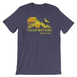 May include: A navy blue t-shirt with a yellow graphic of mountains, a sun, and a bird. The text "Yellowstone National Park" is printed in yellow below the graphic.