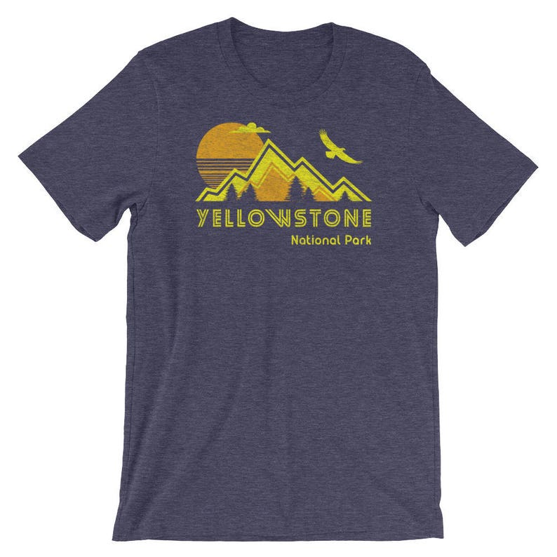 May include: A navy blue t-shirt with a yellow graphic of mountains, a sun, and a bird. The text "Yellowstone National Park" is printed in yellow below the graphic.