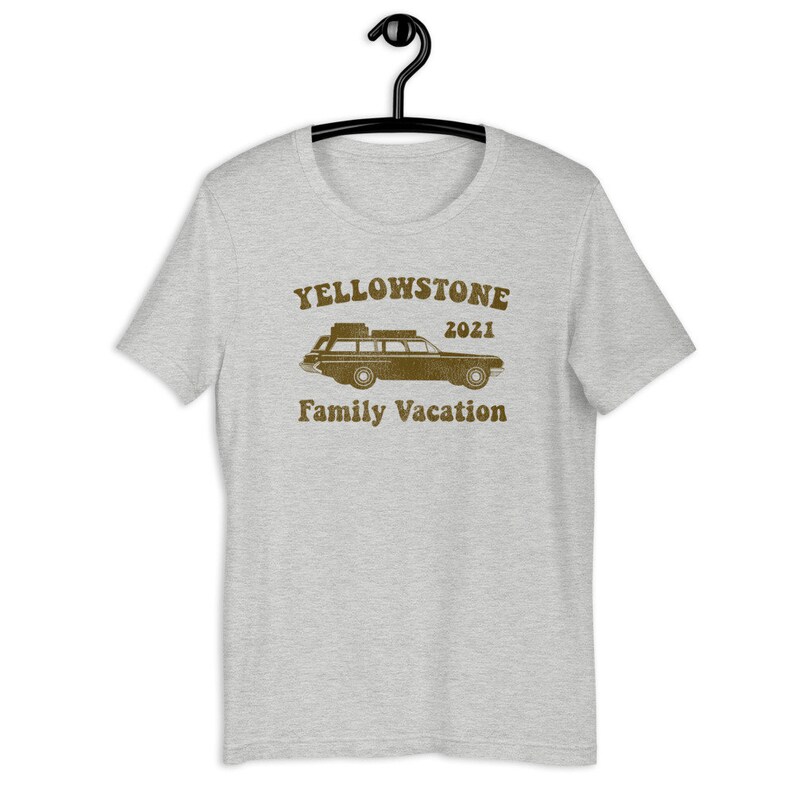 May include: A heather grey t-shirt with a brown graphic of a vintage station wagon with luggage on the roof. The text "Yellowstone 2021 Family Vacation" is printed below the car.