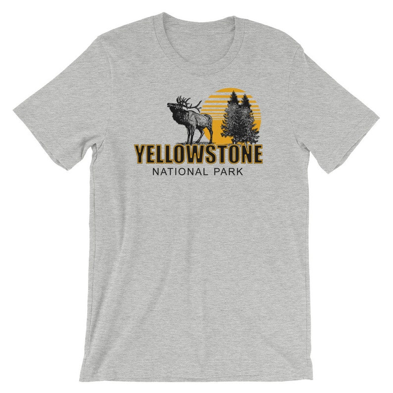 May include: Gray t-shirt with a black and white illustration of an elk and trees with a yellow sun behind them. The text "Yellowstone National Park" is printed in black on the shirt.
