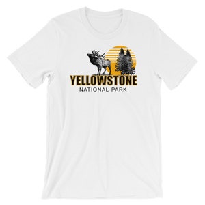 May include: White t-shirt with a black and white illustration of an elk and trees with a yellow sun behind them. The text "Yellowstone National Park" is printed in black with a yellow outline.
