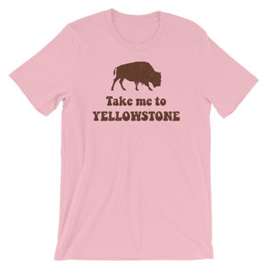 May include: Pink t-shirt with a brown silhouette of a bison and the text "Take me to Yellowstone" in brown.