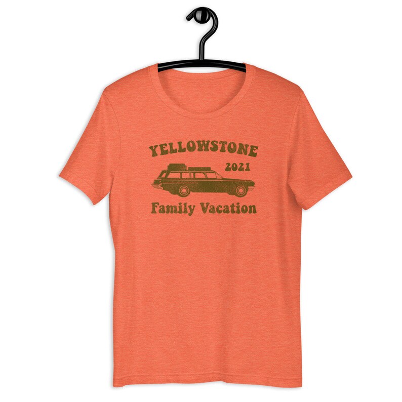 May include: Orange t-shirt with a vintage-style graphic of a station wagon with luggage on the roof. The text "Yellowstone 2021 Family Vacation" is printed on the shirt.