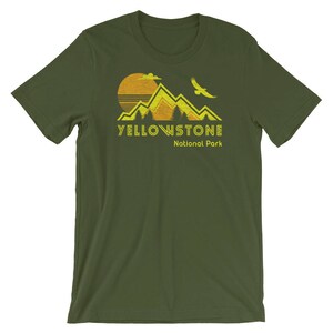 May include: A green t-shirt with a yellow graphic of mountains, a sun, and a bird. The text "Yellowstone National Park" is printed in yellow below the graphic.