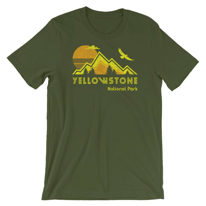 May include: A green t-shirt with a yellow graphic of mountains, a sun, and a bird. The text "Yellowstone National Park" is printed in yellow below the graphic.