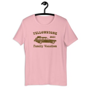May include: Pink t-shirt with a brown graphic of a station wagon with luggage on the roof and the text "Yellowstone 2021 Family Vacation".