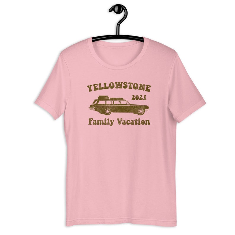 May include: Pink t-shirt with a brown graphic of a station wagon with luggage on the roof and the text "Yellowstone 2021 Family Vacation".