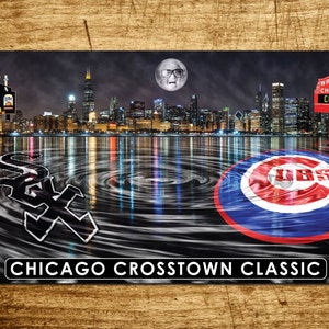 May include: A black and white banner with the Chicago White Sox and Chicago Cubs logos. The logos are in the center of the banner, with a cityscape of Chicago in the background. The banner reads "Chicago Crosstown Classic" at the bottom.