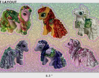 Può includere: Un foglio di sei pony giocattolo colorati con criniere e code fluenti. I pony sono rosa, bianchi, gialli e viola, con decorazioni floreali. Il foglio misura 21,59 cm di larghezza e 13,97 cm di altezza.