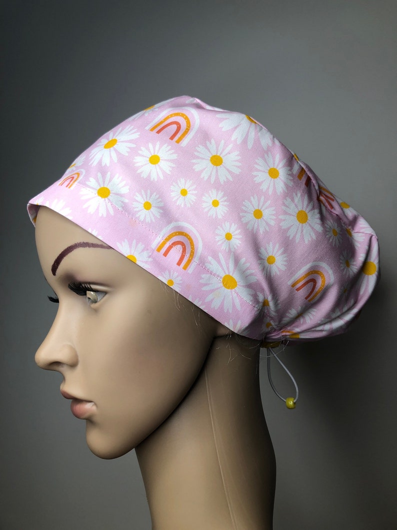 pastel pink surgical scrub cap with yellow and white daisies and cute rainbows euro elastic toggle style to suit long ponytails