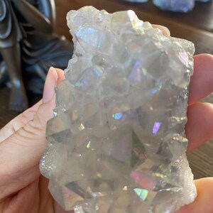May include: A cluster of iridescent white quartz crystals with a rainbow sheen. The crystals are clustered together in a natural formation.