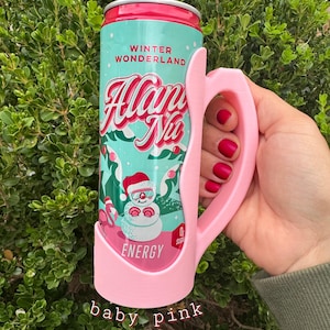 K&ouml;nnte beinhalten: Ein babyrosa Dosenhalter mit Griff, der eine Dose Energy-Drink "Winter Wonderland" h&auml;lt. Die Dose zeigt eine Schneemann-Grafik und die Worte "Alan Nu". Der Halter wird von einer Hand mit rotem Nagellack gehalten.