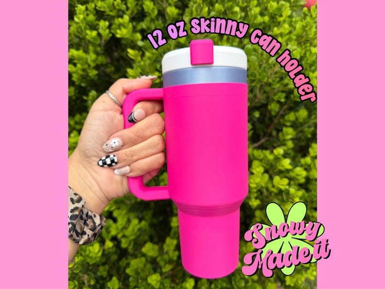 May include: A bright pink 12 oz skinny can holder with a white lid and handle. The can holder has the text "12 oz skinny can holder" and "Snowy Made It" in a playful font.
