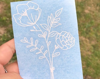 May include: White vinyl sticker with a floral design. The design features three flowers and leaves. The flowers are stylized and have a simple, modern look.