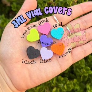 May include: A collection of 3ml vial covers shaped like hearts in various colors including lime green, pink, teal, lavender, black, lilac, and orange. The text 3ML VIAL COVERS is printed at the top, and individual color names are labeled near each heart.