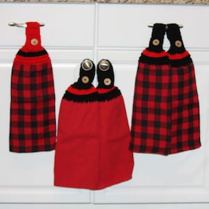 May include: Three red and black checkered kitchen towels with crocheted black and red trim and wooden buttons.