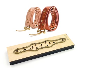 May include: Two leather belts, one brown and one pink, are wrapped around each other. The belts have brass buckles and are lying on a wooden cutting die with the number X050415 printed on it.