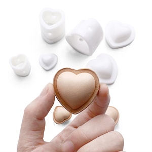 Può includere: Un set di sette stampi a forma di cuore bianchi per realizzare cioccolato o altri dolcetti. Gli stampi sono in silicone e sono facili da usare e pulire. Gli stampi sono mostrati con un dolcetto a forma di cuore finito.