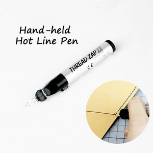 May include: A silver and black hand-held hot line pen with the text "THREAD ZAP III" and "CE" on the side. The pen is used to create a line on leather for stitching.