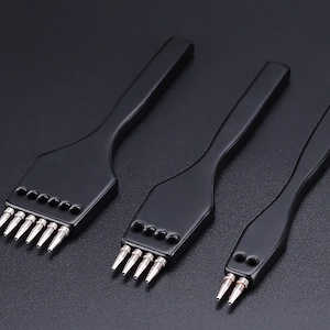 以下が含まれることがあります： 異なるサイズのヘッドを持つ3つの黒い革穴あけツール。各ツールには黒いハンドルと、革をパンチするための複数の穴のある銀色の金属ヘッドがあります。