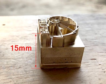 May include: A brass stamp with a 15mm square base and a design featuring a spiral and the word "ALIVE".