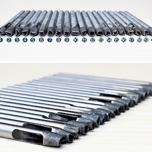 K&ouml;nnte beinhalten: Ein Satz von 20 Metall-Lederlocher mit verschiedenen Formen, darunter Kreise, Quadrate, Sterne, Herzen und mehr. Die Locher sind in zwei Reihen angeordnet, wobei die erste Reihe die verschiedenen Formen zeigt und die zweite Reihe die Locher in einem Stapel zeigt.