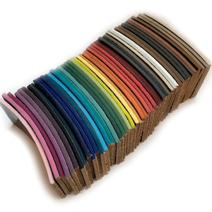 Op de afbeelding: Een stapel lederen stroken in verschillende kleuren, waaronder roze, paars, blauw, groen, geel, oranje, rood, bruin en zwart.