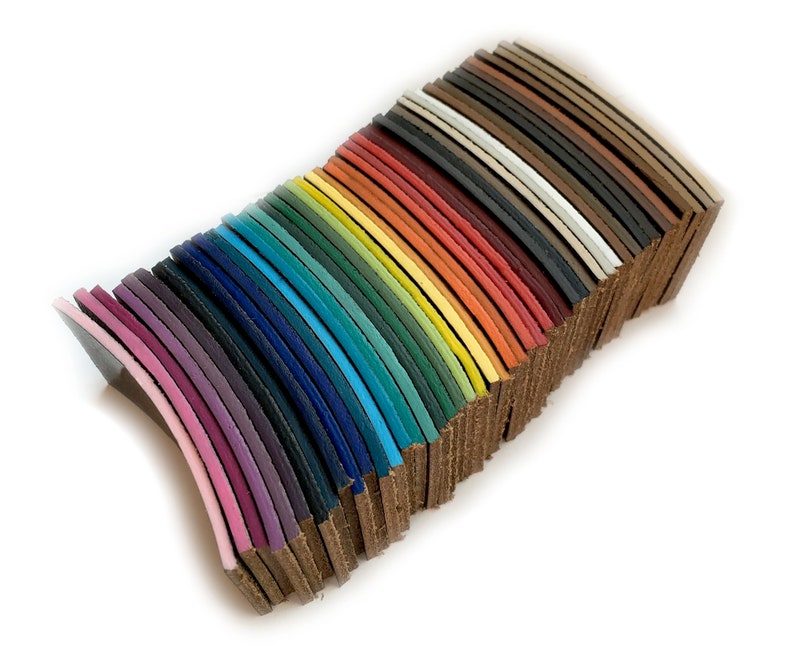 Op de afbeelding: Een stapel lederen stroken in verschillende kleuren, waaronder roze, paars, blauw, groen, geel, oranje, rood, bruin en zwart.