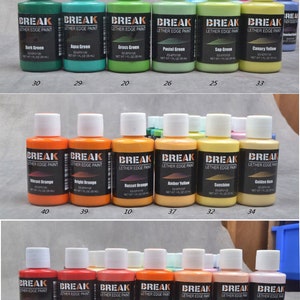 Op de afbeelding: Een set van 48 kleine flesjes lederrandverf in verschillende kleuren, waaronder blauw, groen, oranje, rood, bruin en geel. Elk flesje is gelabeld met de merknaam "Break" en de kleurnaam. De flesjes zijn gerangschikt in rijen van zes, met de nummers 1 tot en met 48 onder elke rij gedrukt.