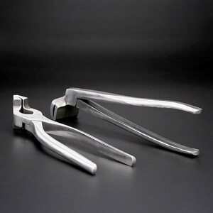 May include: Two silver metal pliers with long handles. The pliers are designed for bending metal.