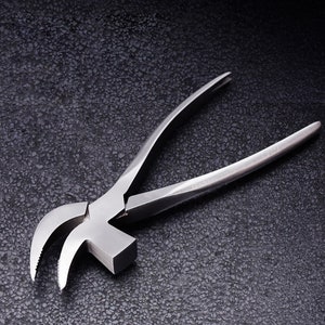 May include: A silver metal hammer with a curved claw and a serrated edge. The hammer is designed for pulling nails and is a tool for construction and DIY projects.