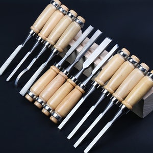 May include: A set of 10 wood carving chisels with wooden handles. The chisels are arranged in a wooden holder. The chisels are made of metal and have different sizes and shapes.